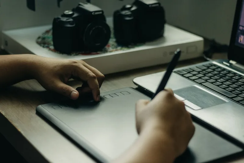 Person designing a digital product template on a laptop with design software on screen