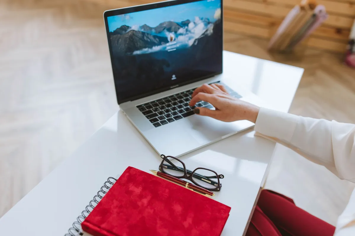 Person working at a clean desk with laptop and notebook, creating a digital product