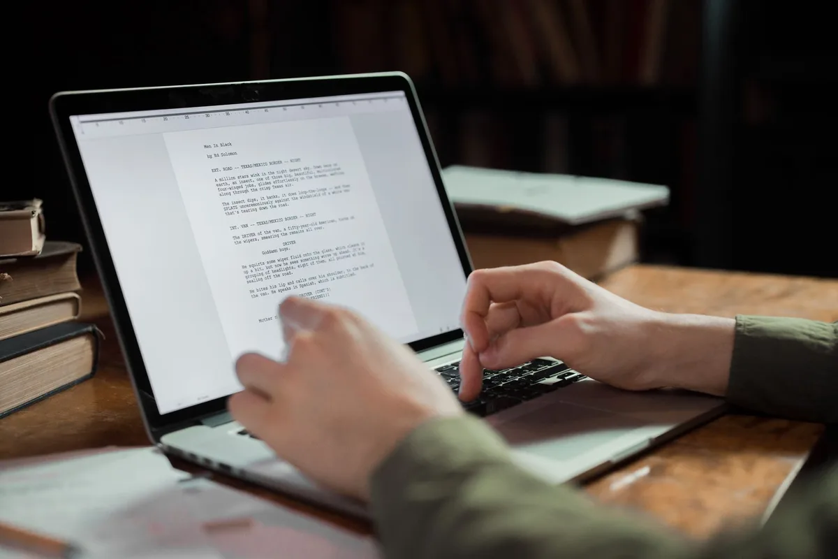 Person working at a desk with a laptop and notebook, drafting content