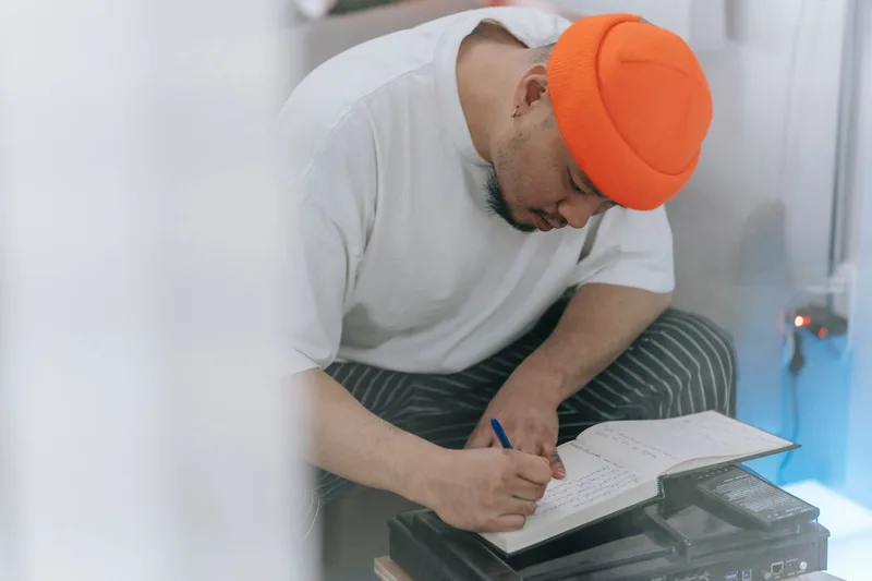 Person taking notes in a notebook while planning content at a desk