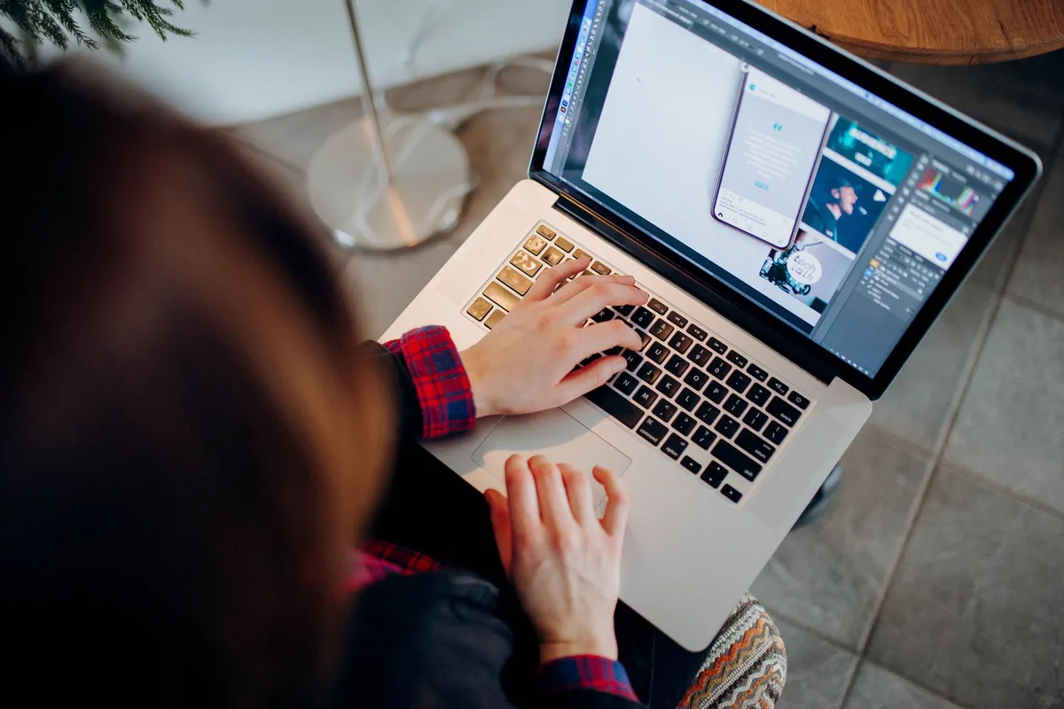 Creator at laptop with Canva open designing a digital product at a clean home office desk