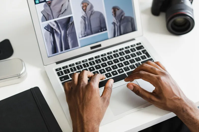 Woman photographing digital products for an online shop with packaging and a laptop visible