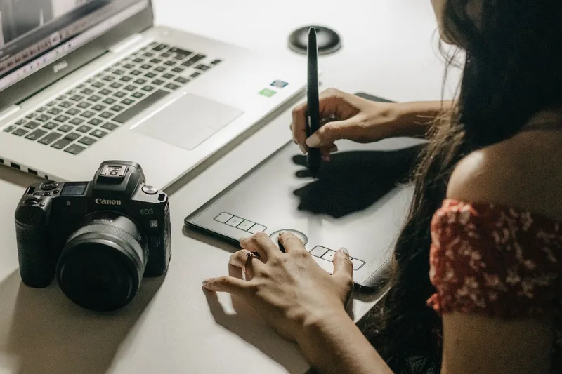 A digital drawing tablet and laptop set up on a desk for creative digital product work